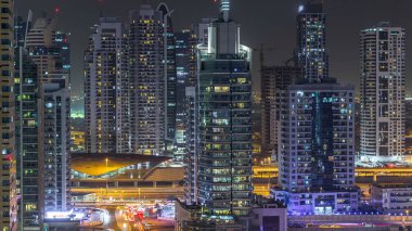 Konut kuleleri aydınlatma ve aydınlatma timelapse ile. Yol ve Dubai Yat Limanı ve Jlt manzarası, gece güvertede. Rating gökdelenler ile parlayan pencere eşiği yanında