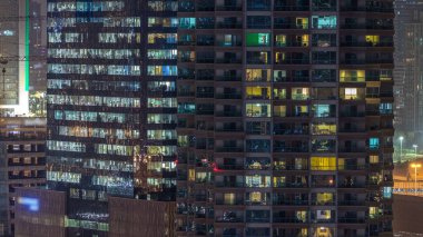 Windows çok katlı binanın içinde aydınlatma ve insanlar timelapse içinde hareketli çelik ve cam. Modern konut ve ofis gökdelenler Dubai Marina havadan görünümü