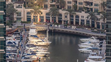 Promenade ve lüks gökdelenler ve yatlar çevresinde timelapse, Birleşik Arap Emirlikleri Dubai Marina kanal. Gün batımı sırasında hava üstten görünüm