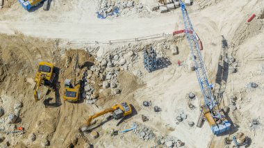 Büyük inşaat alanında bir bina kompleksinde çalışma birkaç ekskavatör ve vinçler timelapse dahil olmak üzere. Hava üstten görünüm yukarıdan güneşli gün, Dubai, Birleşik Arap Emirlikleri