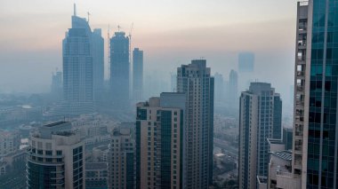 Sisli sabah gün geçiş timelapse gecesine Dubai şehir merkezinde. Şehir gökdelenler fütüristik görünümünü sis kaplı. Çatı güneş doğmadan önce havadan görünümden. Dubai, Birleşik Arap Emirlikleri