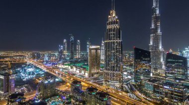 Dubai şehir merkezindeki Ufuk Çizgisi Gece Saati. En yüksek bina ve karayolu trafiği, BAE. Gökdelenin çatısından aydınlatmalı modern kuleleri olan havadan panoramik manzara