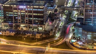 Dubai şehir merkezi gökyüzü çizgisi gece zaman çizelgesi ve karayolu trafiği, BAE. Gökdelenin çatısından gökdelen manzarası aydınlanmış modern ofis binalarıyla