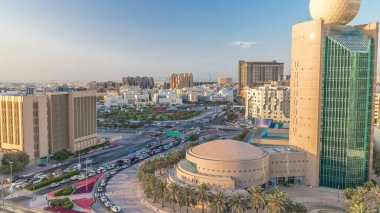 Dubai Creek bölgesi modern binalar ve kalabalık trafik sokağı panoramik zaman çizelgesiyle çevrili. Gün batımında uzun gölgeler ve turuncu ışıkla yukarıdan gökyüzü manzarası