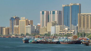 İskele tarafındaki ahşap botları değiş tokuş ediyorlar. Nehir Kanalı 'ndaki ticaret gemileri. Deira 'daki gökdelenler. Form köprüsünü göster