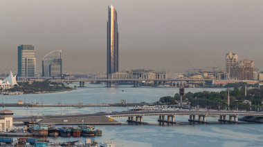 Dubai creek manzara timelapse tekneler ve bağlantı noktası, sakin su ve gün batımı sırasında arka planda modern binalar gemi ile. Gökdelen yansıyan güneş ile yukarıdan hava üstten görünüm