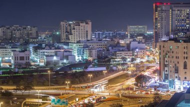 Dubai Creek alan modern binalar ve yoğun trafik sokak gece geçiş timelapse çevrili. Işıklandırılmış gökdelenler ve metro istasyonu ile yukarıdan hava üstten görünüm