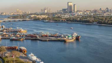 Dubai deresi zaman çizelgesi, limanda tekne ve gemi, sakin su ve günbatımında modern binalar. Yukarıdan iskelenin havadan görünümü