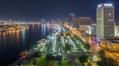 Dubai creek manzara gece timelapse tekneler ve yatlar ve trafik yol ve otopark ile modern binalar ile. Yukarıdan hava üstten görünüm