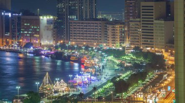 Dubai creek manzara gece timelapse tekneler ve yatlar ve trafik yol ve otopark ile modern binalar ile. Yukarıdan hava üstten görünüm