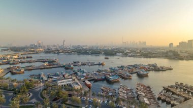 Dubai creek manzara timelapse tekneler ve gün batımı sırasında arka planda şehir gökdelenler ile bağlantı noktası, sakin su ve modern binalar gemi ile. Yukarıdan hava üstten görünüm
