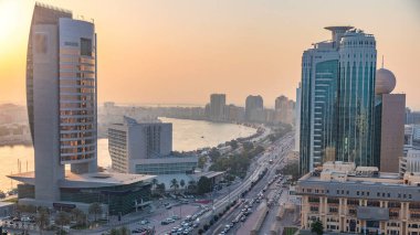 Günbatımında Dubai deresi manzarası. Tekneler, yatlar ve yol ve araba parkı trafiği olan modern binalar. Yukarıdan turuncu gökyüzü ile gökyüzü görüntüsü