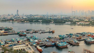 Dubai creek manzara timelapse tekneler ve gün batımı sırasında arka planda şehir gökdelenler ile bağlantı noktası, sakin su ve modern binalar gemi ile. Yukarıdan hava üstten görünüm
