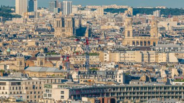 Paris 'teki evlerin çatılarının üstündeki hava manzarası. Günbatımından önce Notre Dame de Paris ve Saint-Sulpice 'in akşam manzarası. İnşaat alanındaki vinçler
