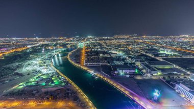 Downtown gökdelenler çatıdan yaya köprüsü havadan gece timelapse ile Dubai su kanalı. Işıklı rıhtım. Yüzer tekneler ve vinçli şantiye