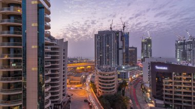 Gün batımından sonra Dubai Marina 'da gökdelenler ve hava yürüyüşü gününden geceye geçiş zamanı. Yol trafiği olan modern kuleler ve tekneler. Birleşik Arap Emirlikleri