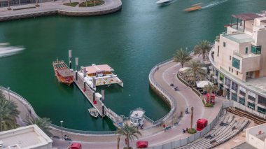 Dubai Marina Limanı 'ndaki rıhtım güvertesi, zaman ayarlı. Kanalda yüzen tekne ve yatlar. Dubai, Birleşik Arap Emirlikleri