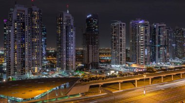 Dubai Marina 'dan Şeyh Zayed yoluna giden hava panoramik manzaralı Jlt aydınlatmalı gökdelenler, gece zaman çizelgesi, Dubai. Trafik ve metro istasyonu. Birleşik Arap Emirlikleri