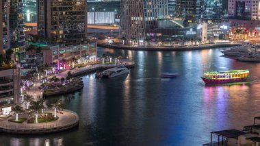 Dubai Marina Limanı 'ndaki rıhtım güvertesi gece uçuşları. Kanalda yüzen tekne ve yatlar. Dubai, Birleşik Arap Emirlikleri