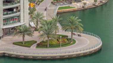 Dubai Marina 'da avuçiçi avuçlarla rıhtım gezintisi. Kanalda yüzen tekne ve yatlar. Dubai, Birleşik Arap Emirlikleri