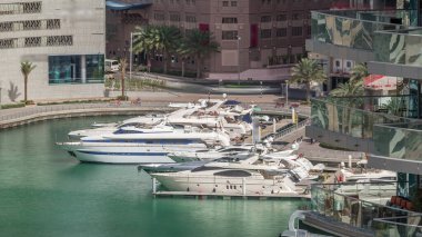 Dubai Marina Limanı 'ndaki rıhtım güvertesi, zaman ayarlı. Kanalda yüzen tekne ve yatlar. Dubai, Birleşik Arap Emirlikleri