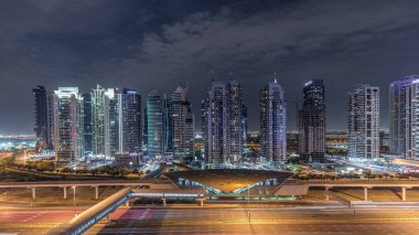 Dubai Marina 'dan Şeyh Zayed yoluna giden hava panoramik manzaralı Jlt aydınlatmalı gökdelenler, gece zaman çizelgesi, Dubai. Trafik, köprüler ve metro hattı. Birleşik Arap Emirlikleri