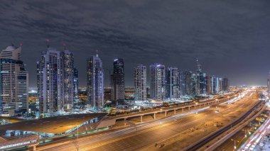 Dubai Marina 'dan Şeyh Zayed yoluna giden hava panoramik manzaralı Jlt aydınlatmalı gökdelenler, gece zaman çizelgesi, Dubai. Trafik, köprüler ve metro hattı. Birleşik Arap Emirlikleri