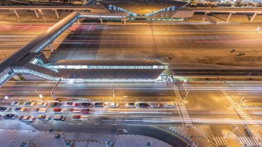Dubai Marina yakınlarındaki Şeyh Zayed yoluna ve Dubai 'deki Jlt gece zaman ayarlı hava manzarası. Otoyolda trafik, metro ve tramvay istasyonları arasında yaya köprüsü. Birleşik Arap Emirlikleri
