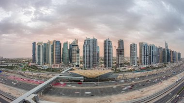 Dubai Limanı 'ndan Şeyh Zayed yoluna giden hava panoramik manzara. Dubai' deki Jlt aydınlatmalı gökdelenler, gece ve gündüz geçiş zamanı. Trafik, köprüler ve metro istasyonu. Birleşik Arap Emirlikleri