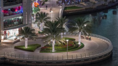 Dubai Marina hava sahasında palmiyeler daireler çizerek rıhtımda geziniyor. Kanalda yüzen tekne ve yatlar. Dubai, Birleşik Arap Emirlikleri