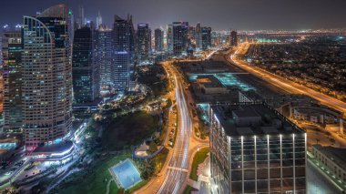 Jumeirah Lake Towers yerleşim bölgesi Dubai Marina yakınında hava gece timelapse. Işıklı modern gökdelenler ve yukarıdan trafik