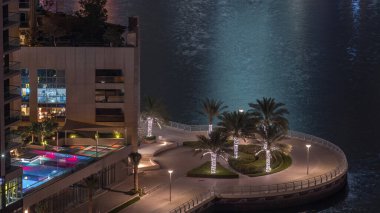 Dubai Marina hava sahasında palmiyeler daireler çizerek rıhtımda geziniyor. Kanalda yüzen tekne ve yatlar. Dubai, Birleşik Arap Emirlikleri