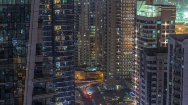 Dubai Marina 'daki çeşitli gökdelenlerin ve kulelerin görüntüsü. Kentsel gökdelendeki aydınlanmış modern binalar ve caddelerde trafik