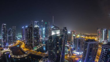 Dubai limanının panoramik manzarası ve tüm gece boyunca deniz manzaralı ofis gökdelenleri ışıkların kapandığı yer. Yüzen tekneler ve yatlar