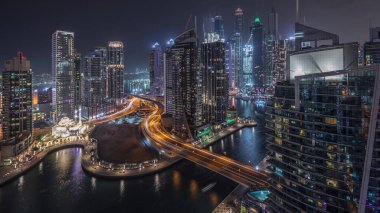Dubai Marina konutlarının ve ofis gökdelenlerinin deniz kenarında gece trafiği olan hava manzarası. Yüzen tekneler ve yatlar