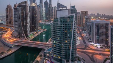Dubai Marina yerleşim yerlerinin ve ofis gökdelenlerinin hava panoramik görüntüsü. Köprü ve rıhtımda gece gündüz trafik var. Gün doğumundan önce geçiş zamanı. Yüzen tekneler ve yatlar