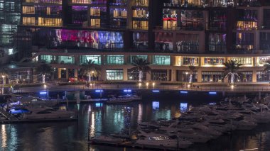 Dubai Marina Limanı 'ndaki rıhtım güvertesi gece uçuşları. Kanalda yüzen tekne ve yatlar. Dubai, Birleşik Arap Emirlikleri