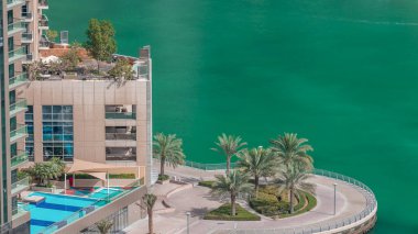 Dubai Marina 'da avuçiçi avuçlarla rıhtım gezintisi. Kanalda yüzen tekne ve yatlar. Dubai, Birleşik Arap Emirlikleri