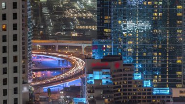 Jbr ve Dubai marina hava gece timelapse de köprüde trafik. Kanal yakınındaki ışıklı modern kuleler ve gökdelenler