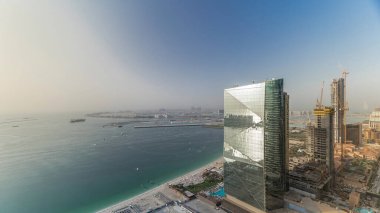 Dubai Jumeirah plaj rezidans Modern gökdelenler, gün batımı sırasında bir arka plan üzerinde palmiye Jumeirah ile Jbr havadan timelapse