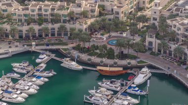 Dubai marina timelapse yüzen yatlar üzerinde havadan görünümü. Beyaz tekneler yeşil kanal suyunda. Mağaza ve restoranlar ile gezinti.