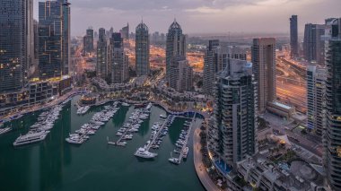 Dubai Marina gece gündüz geçiş timelapse havadan üst görünümü. Dubai, Bae gün doğumundan önce yüzen yatlar ve tekneler ile gezinti ve kanal. Işıklı modern kuleler ve yolda trafik