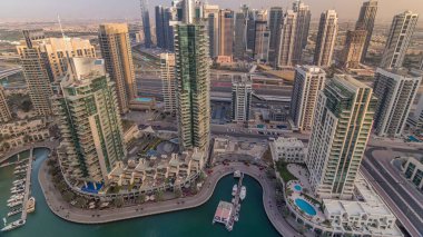 Dubai Marina ve Jlt akşam timelapse havadan üst görünümü. Dubai, Bae'de gün batımından önce yüzen yatlar ve tekneler lezne ve kanal. Modern kuleler ve yolda trafik