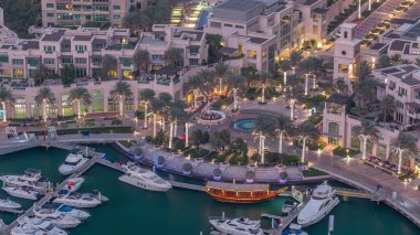 Dubai Marina'nın havadan üstten gündüz geceye geçiş saati. Dubai, Bae gün batımından sonra yüzen yatlar ve tekneler ile gezinti ve kanal. Işıklı binalar ve çeşme