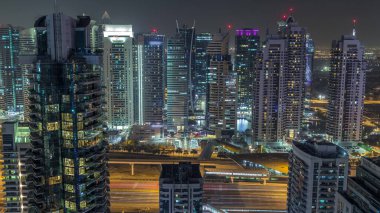 Dubai Marina ve Jlt gece zaman atlamalı havadan üst görünümü. Dubai, Bae yukarıdan gökdelenler. Işıklı modern kuleler ve yolda trafik