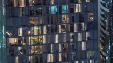 Ofis ve apartmanın gece görüşü. Pencereleri yanıp sönen gökdelenli ve içinde insanlar olan bir gökdelen. Yukarıdan hava görünümü