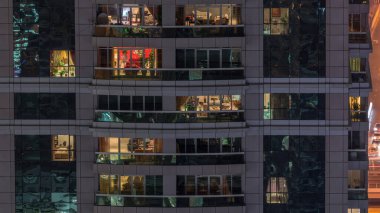 Dış binanın gece görüşü zaman ayarlı. Pencerelerinde yanıp sönen ışıklar olan yüksek gökdelenli insanlar içeri giriyor.
