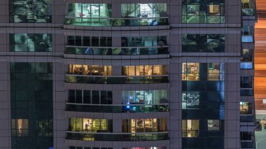 Dış binanın gece görüşü zaman ayarlı. Pencerelerinde yanıp sönen ışıklar olan yüksek gökdelenli insanlar içeri giriyor.