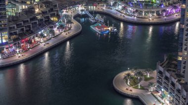 Dubai Marina Havaalanı 'ndaki avuçiçi ve restoranlarla dolu rıhtım güvertesi. Kanalda yüzen tekne ve yatlar. Dubai, Birleşik Arap Emirlikleri