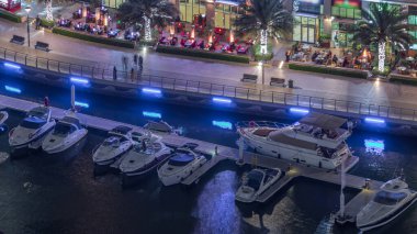 Dubai Marina Havaalanı 'ndaki restoranlarla rıhtım gezintisi. Kanalda yüzen tekne ve yatlar. Dubai, Birleşik Arap Emirlikleri